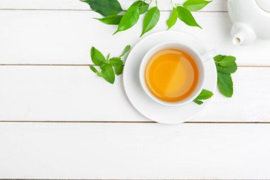 Çaydanlık ve fincanlar beyaz ahşap arka planda.