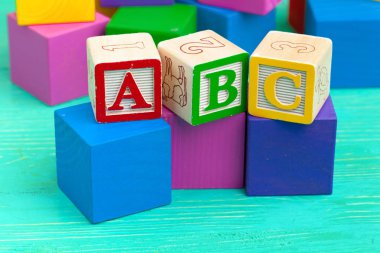 Alfabe alfabesi ABC bloklarını ahşap masaya koyar..