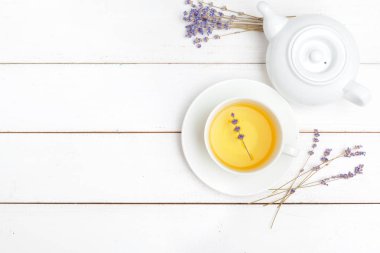 Çaydanlık ve fincanlar beyaz ahşap arka planda.