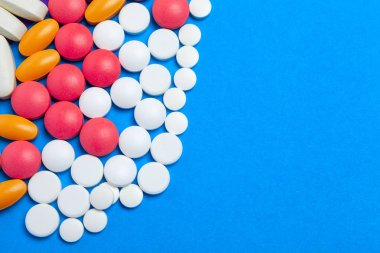 Mavi arka planda bir sürü renkli hap. Üst görünüm.