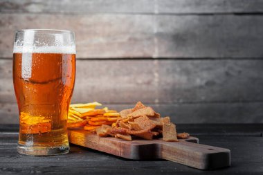 Bira ve aperatifler ahşap masada. Fındık, cips, kraker