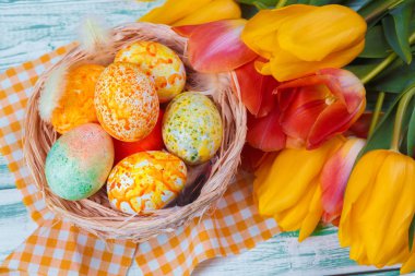 Mavi ahşap arka planda laleleri olan Paskalya yumurtaları