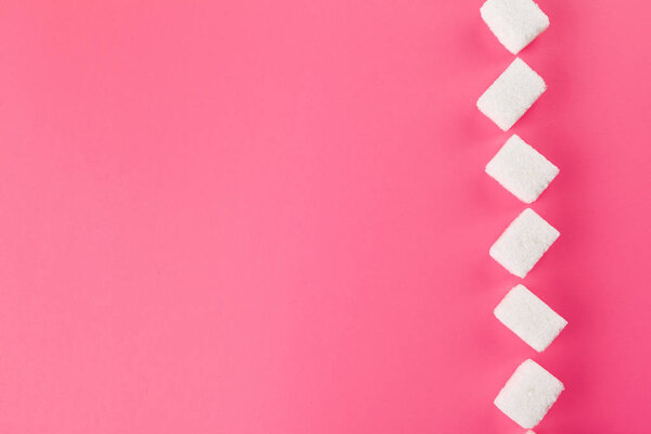 Cubes of sugar on bright pink background