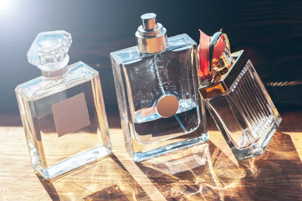 Mehrere Flaschen Mit Parfüm Sonnenstrahlen Auf Holztisch — Stockfoto