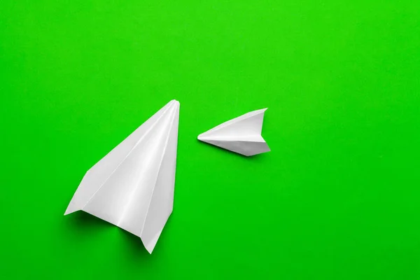 white paper airplane on a green paper background