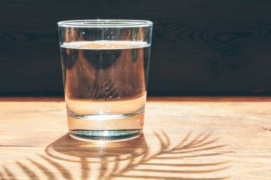 Karanlık arka planda bir bardak su yakın