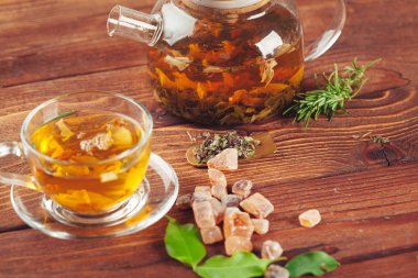 Ahşap masada bir fincan siyah çay ile camdan bir çaydanlık.