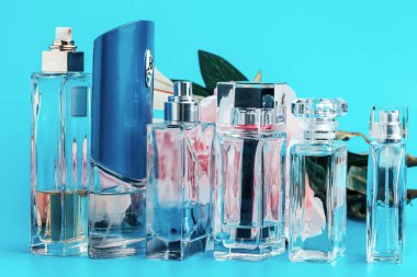 Açık mavi arka planda çiçekli parfüm şişeleri