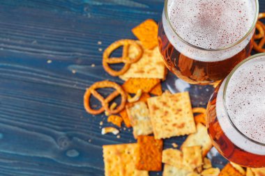 Ahşap arka planda bira ve atıştırmalık bir seçim.