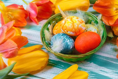 Mavi ahşap arka planda laleleri olan Paskalya yumurtaları