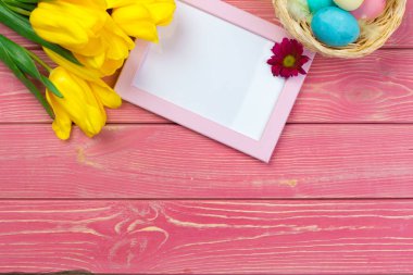 Paskalya konsepti. Renkli arka planda paskalya yumurtaları ve laleleri olan ahşap çerçeve