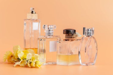 Bej arka planda çiçek yapraklı parfüm şişeleri