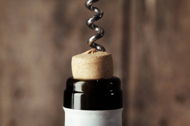 Ahşap arka planda tirbuşonlu bir şişe şarap.