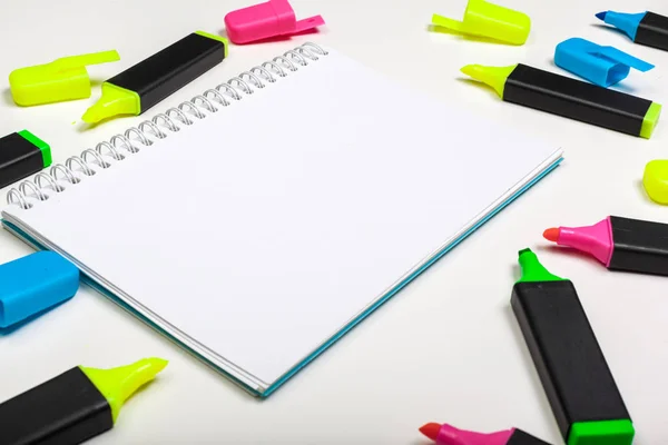 highlighters and  blank notepad paper sheet flat lay on a desk