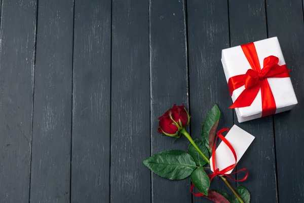 Sevgililer Günü. Kırmızı güller ve hediye kutusu ahşap masada
