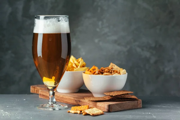 Glass of dark beer with bowl of beer snacks close up