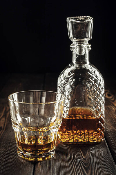 Стакан виски и бутылка на старом деревянном столе