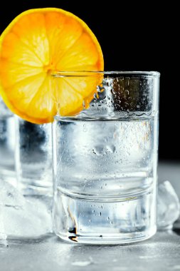 Siyah arka planda shot bardaklarında soğuk votka..