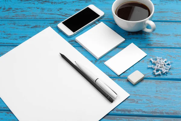 Branding stationery mockup on blue desk. Top view of paper, business card, pad, pens and coffee.