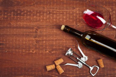 Bir şişe şarap, mantar ve ahşap masada tirbuşon.