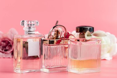 Pembe kumaş arka planında güller olan parfüm şişesi. 