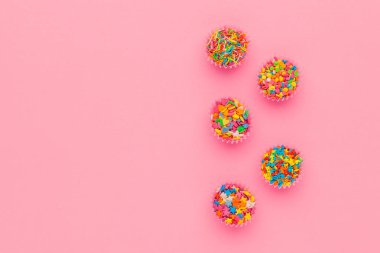 Şeker parçacıkları, pasta, dondurma ve pembe arka planda kurabiyeler için süsleme