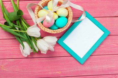 Paskalya, bayram, gelenek ve nesne konsepti - renkli yumurta ve lale çiçeklerinin ahşap arka planda kapatılması