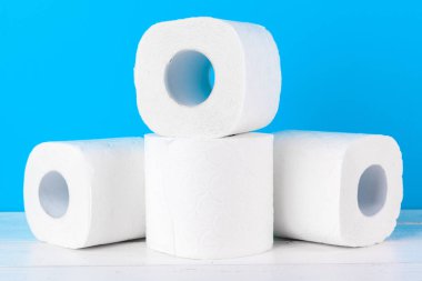 Mavi arka planda istiflenmiş tuvalet kağıdı ruloları