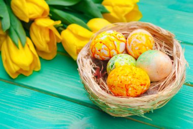 Pastel ahşap arka planda süslü yumurta ve çiçeklerle güzel bir Paskalya kompozisyonu. 
