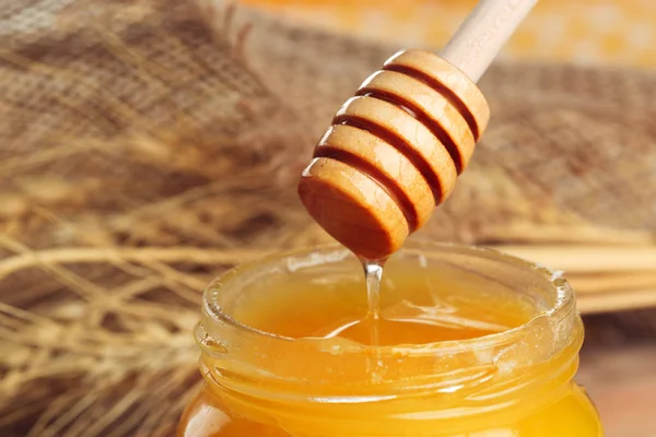 Honey background. Sweet honey in glass jar on wooden background.