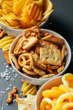 Taş masada bira atıştırmalıkları. Çeşitli krakerler, patates cipsi. Üst görünüm 