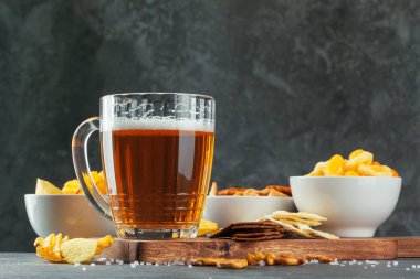 Bir bardak bira ve arka planda atıştırmalık kaseler.