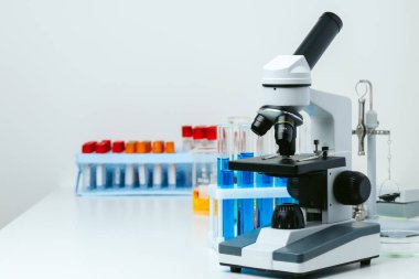 Laboratuvardaki masada mikroskop ve test tüpleri, kapatın.