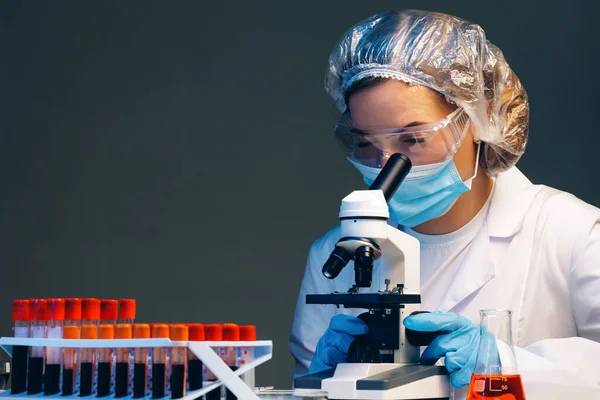 Femme scientifique regardant à travers un microscope en laboratoire — Photo