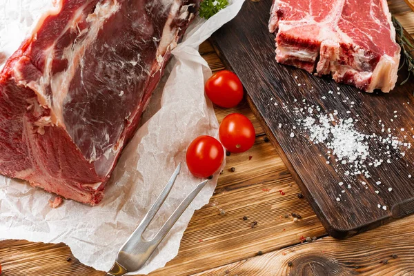 Filete crudo de hueso en T con hierbas sobre tabla de madera — Foto de Stock