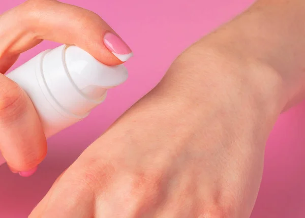 Botella de producto de cuidado de la piel de mano femenina en rosa — Foto de Stock