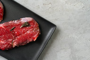 Siyah seramik tabakta iki taze çiğ biftek.