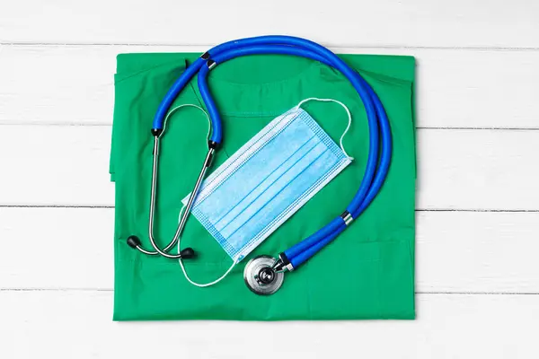 Médico médico uniforme con estetoscopio y mascarilla sobre fondo de madera blanco — Foto de Stock