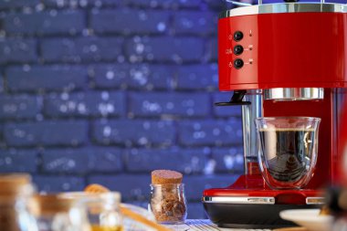 Mutfak tezgahında bardak olan kırmızı kahve makinesi.