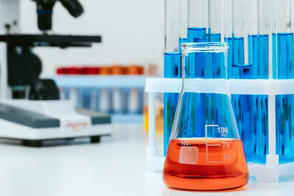 Microscópio e tubos de ensaio na mesa em laboratório, de perto — Fotografia de Stock
