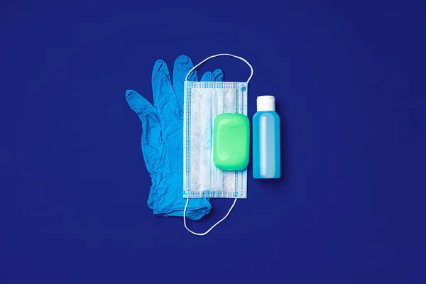 Prevención del Coronavirus. Mascarilla facial, guantes, jabón y desinfectante sobre fondo azul — Foto de Stock