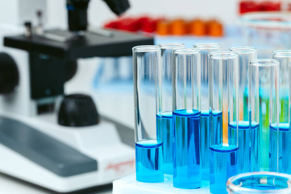 Микроскоп и пробирки на столе в лаборатории, закрыть
