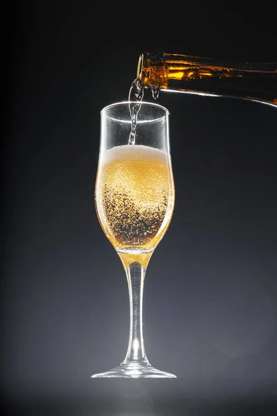 Champagne pouring into glass on black background — Stock Photo, Image
