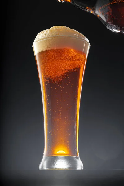Пиво наливається в склянку на чорному тлі — стокове фото