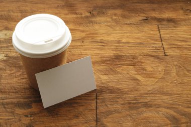 Tahta masada boş kartvizitli kahve fincanı.