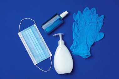 Coronavirus önleme. Mavi arka planda yüz maskesi, eldiven, sabun ve dezenfektan.