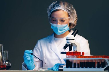 Laboratuvarda üzerinde kan örneği olan test tüpüne bakan kadın bilim adamı.