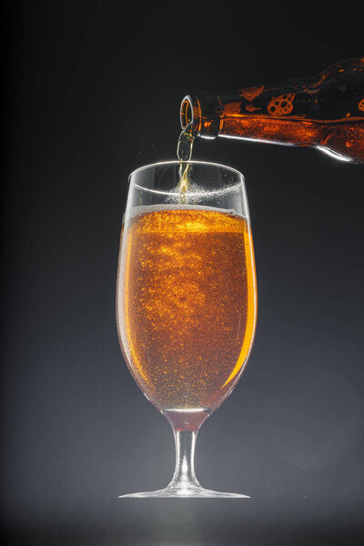 Beer pouring into glass on black background