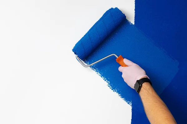 Gloved αρσενικό χέρι ζωγραφική τοίχο σε κλασικό μπλε χρώμα — Φωτογραφία Αρχείου