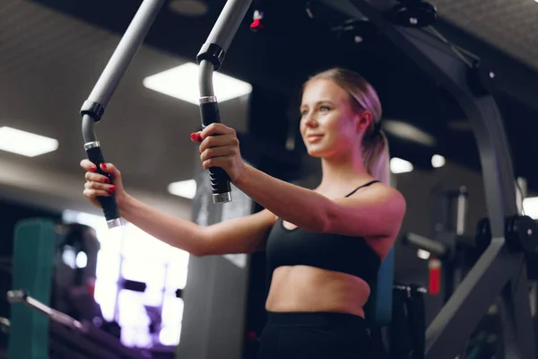 Junge kaukasische blonde Frau trainiert Hände in einem Fitnessstudio — Stockfoto
